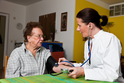 female doctor checking the blood pressure of senior woman